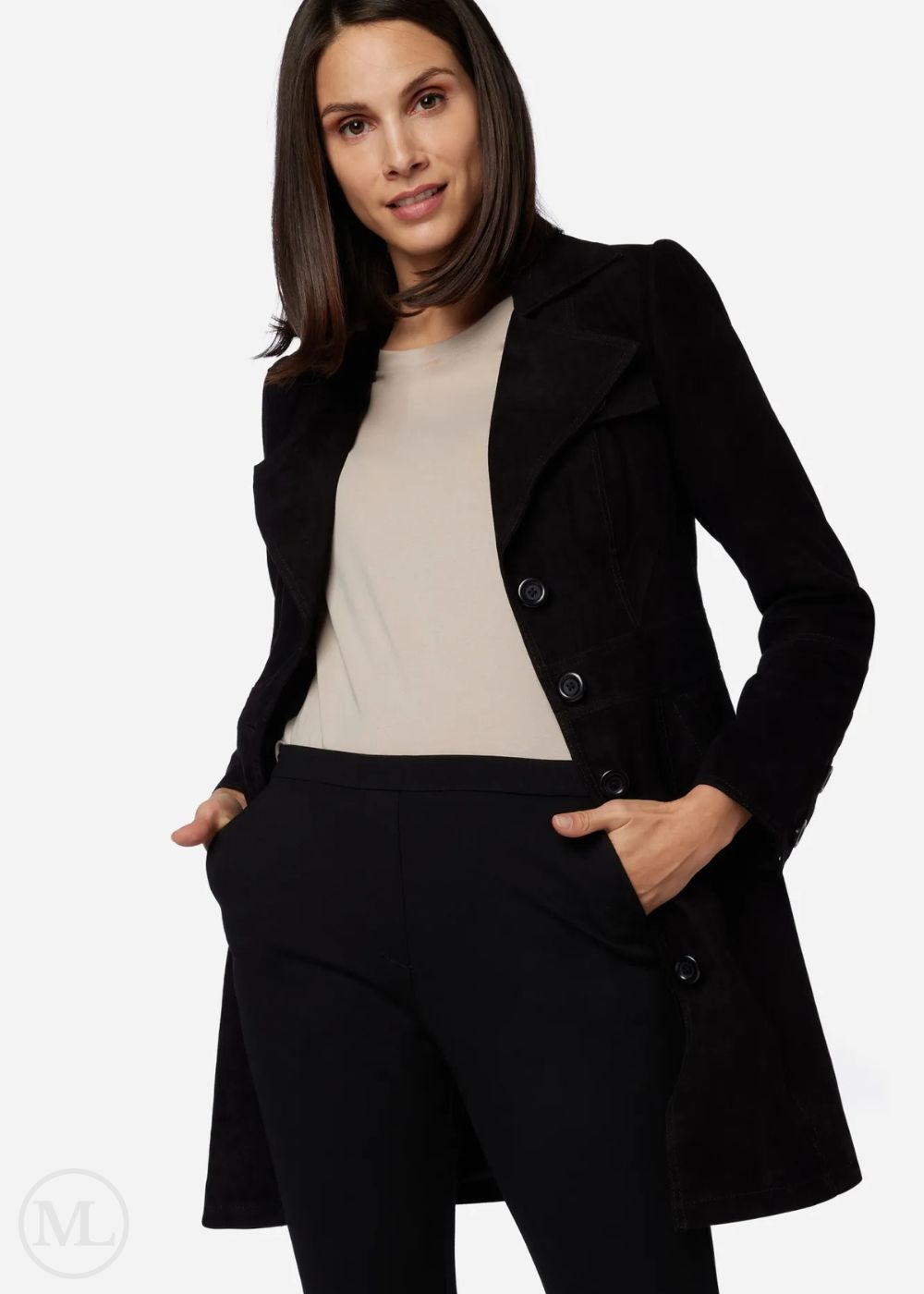 Woman wearing a black coat over a beige top and black pants on a white background