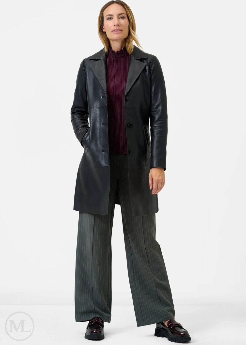 Woman wearing a long black leather coat on a white background