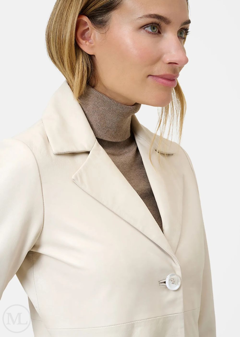 Woman wearing a lvory coat over a brown turtleneck on a white background