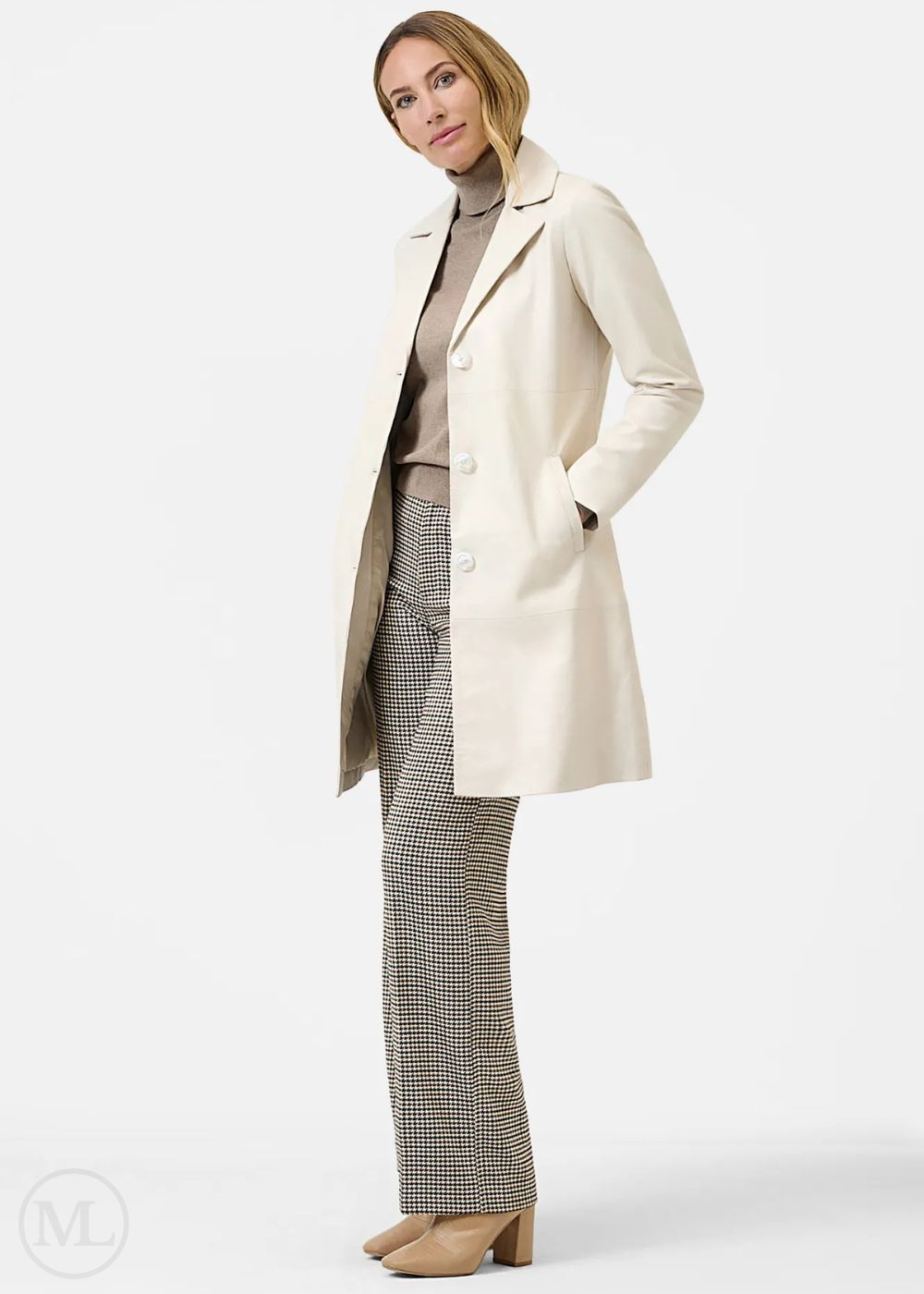 Woman wearing a lvory coat, brown sweater, and plaid pants on a white background