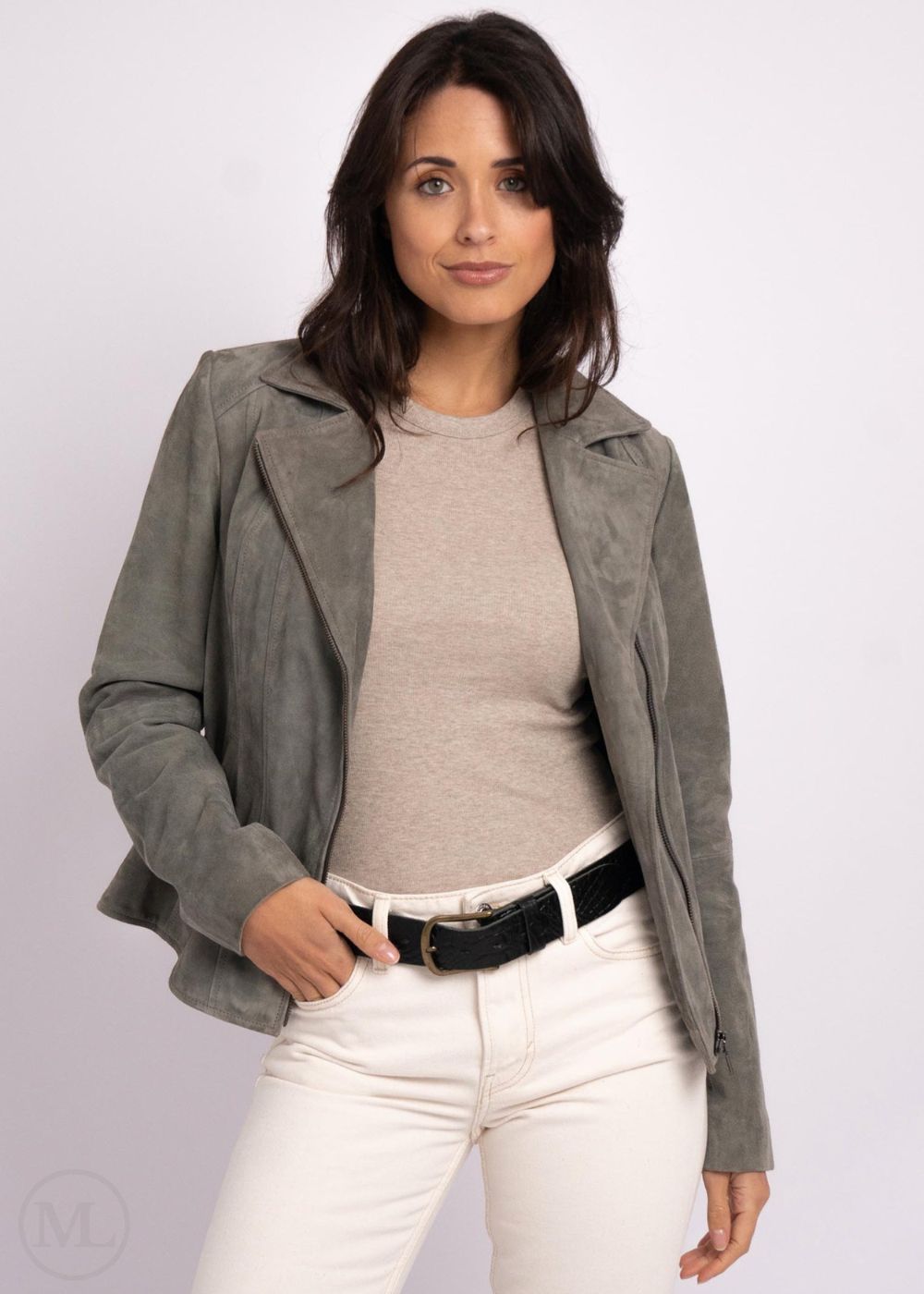 Woman wearing a gray leather jacket, beige top, and white pants on a plain background
