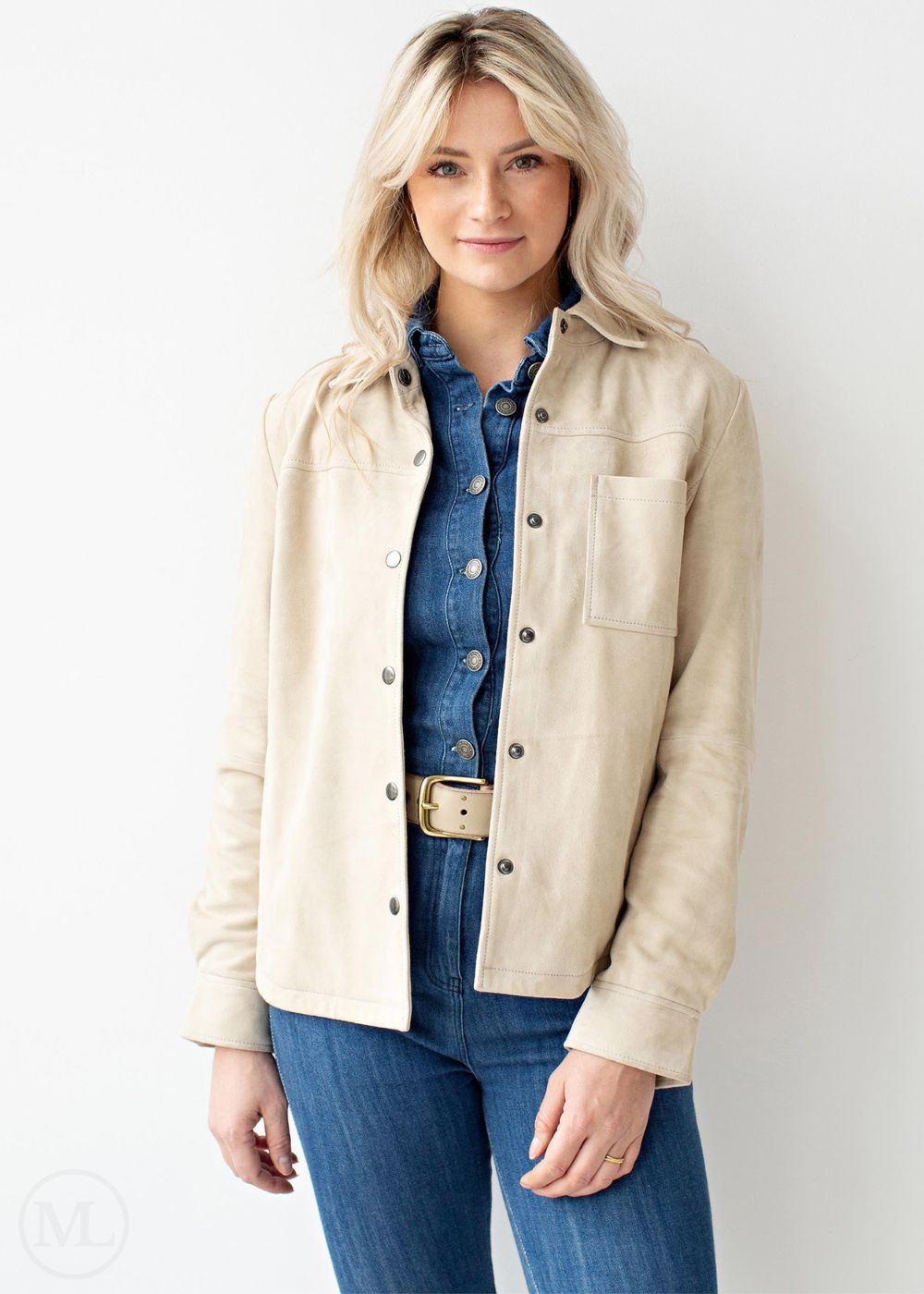 Woman wearing a off white jacket over a denim shirt and jeans on a white background