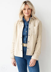Woman wearing a off white jacket over a denim shirt and jeans on a white background