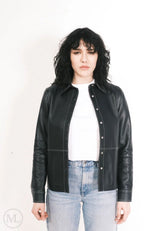 Women wearing a black leather jacket over a white shirt and blue jeans on a white background