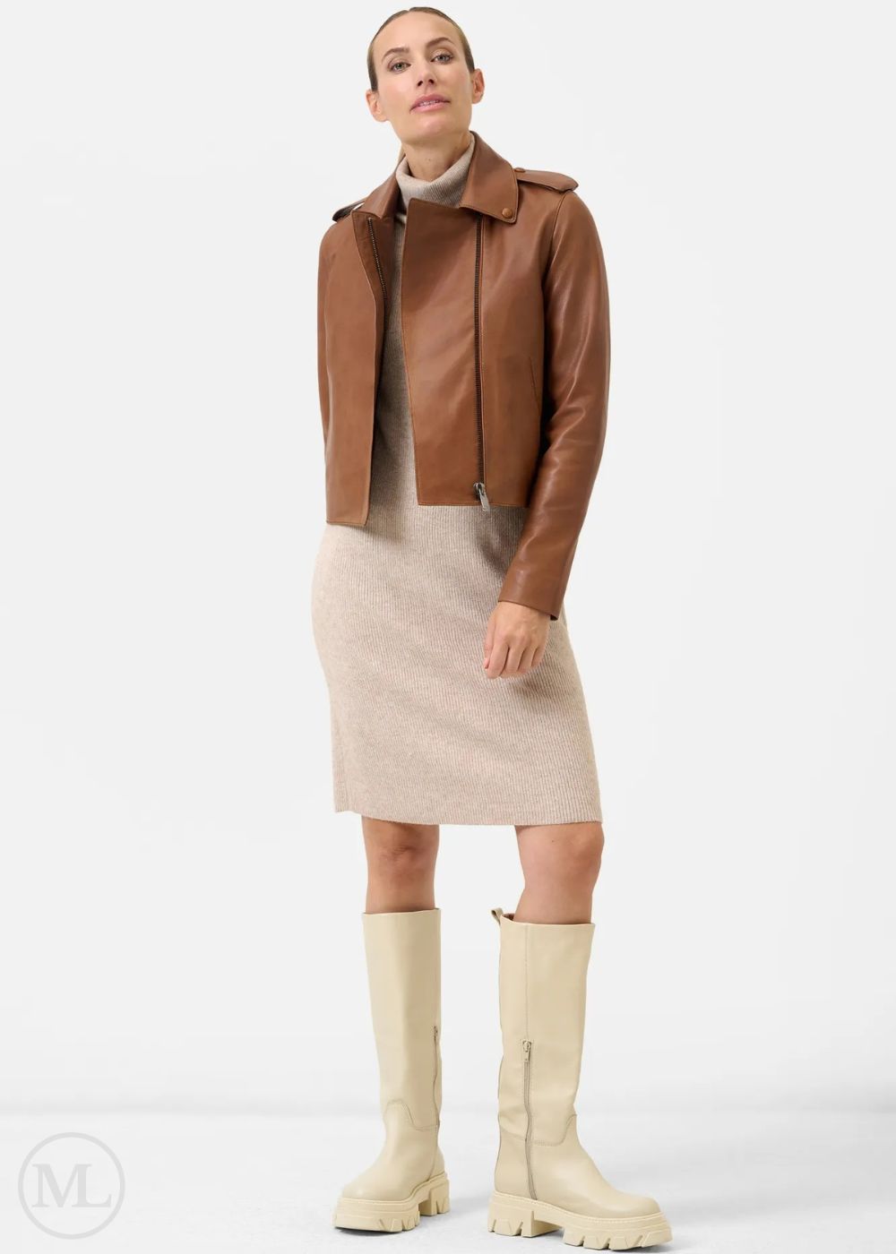 Woman wearing a cognac brown leather jacket, beige dress, and cream knee-high boots on a white background