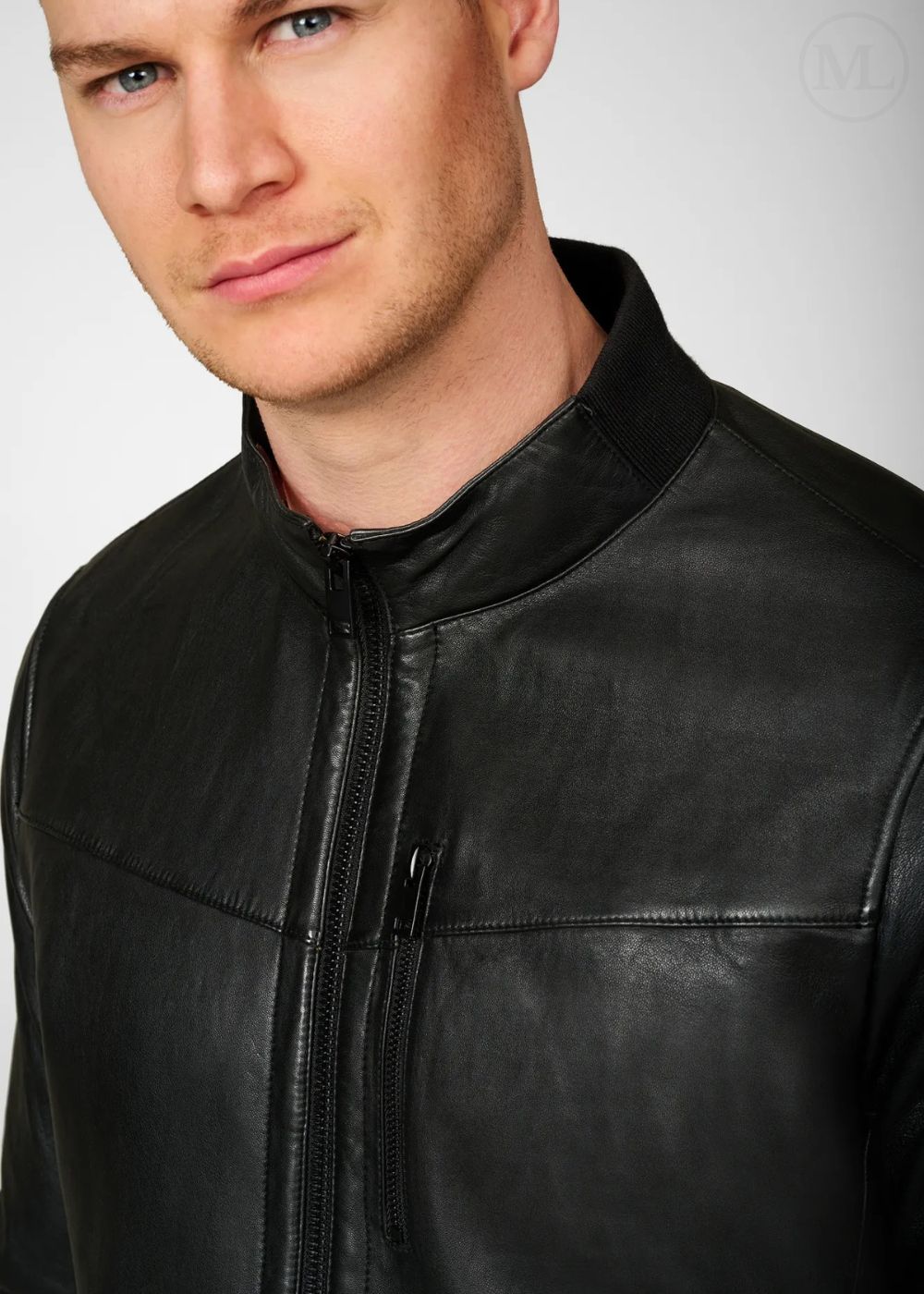 Man wearing a black leather bomber jacket against a plain background