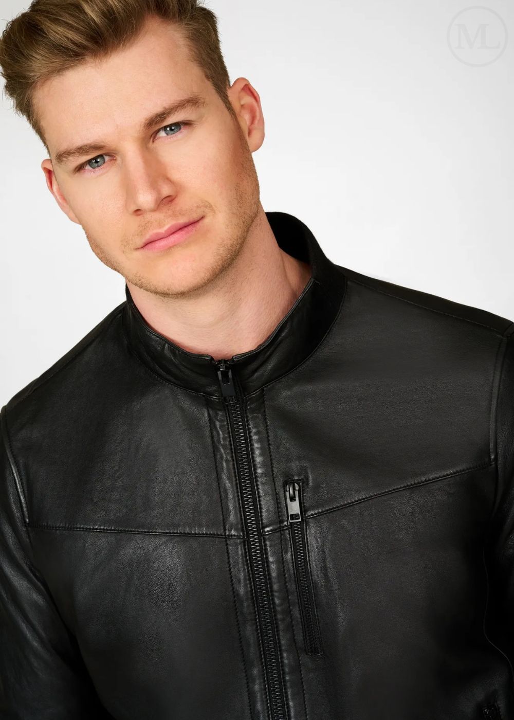 Man wearing a black leather bomber jacket against a plain background