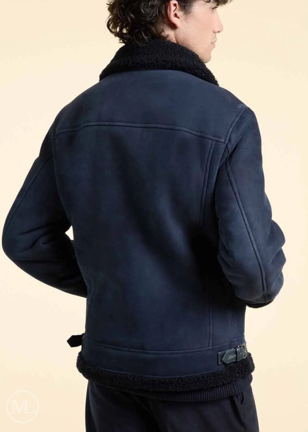 Person wearing a navy blue suede jacket with shearling collar on a beige background