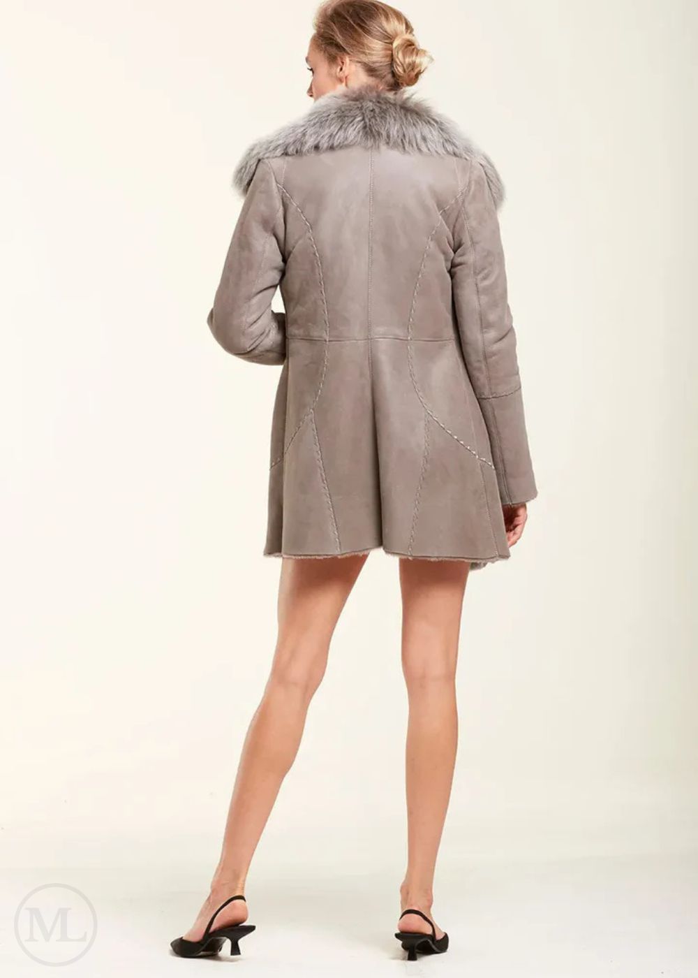 Woman wearing a grey sheepskin coat with fur collar on a white background