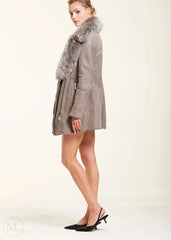 Woman wearing a grey sheepskin coat with fur trim on a white background