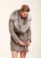 Woman wearing a grey sheepskin coat with a fur collar on a white background