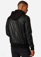 Man wearing a black leather hooded bomber jacket on a plain background