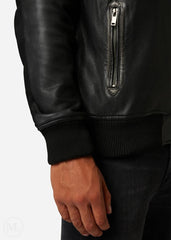 Close-up of a man wearing a black leather hooded bomber jacket with a zipper on a white background