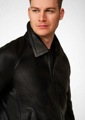 Man wearing a black leather bomber jacket against a white background