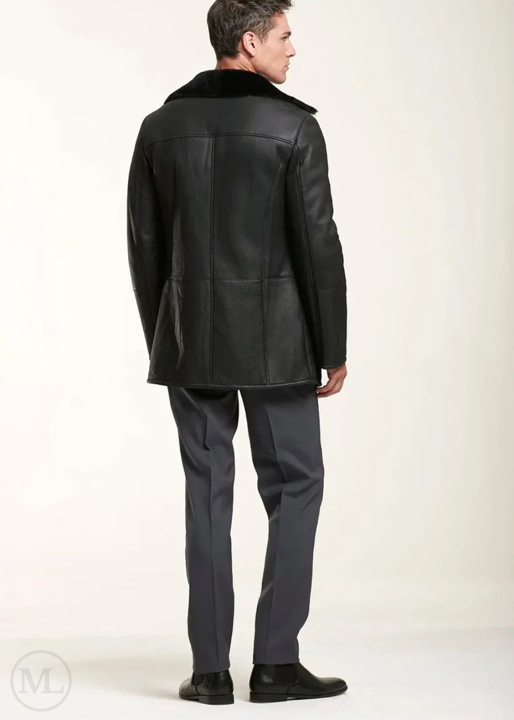 Man wearing a black leather shearling jacket with fur collar on a white background