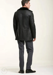 Man wearing a black leather shearling jacket with fur collar on a white background