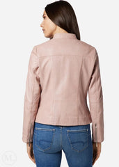 Woman wearing a rose gold leather jacket and blue jeans on a white background