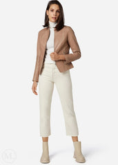 Woman wearing a taupe jacket, white turtleneck, and white pants on a white background