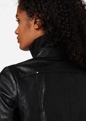 Woman wearing a black leather bomber jacket on a plain background