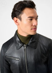 Man wearing a black leather racer jacket with a plain background