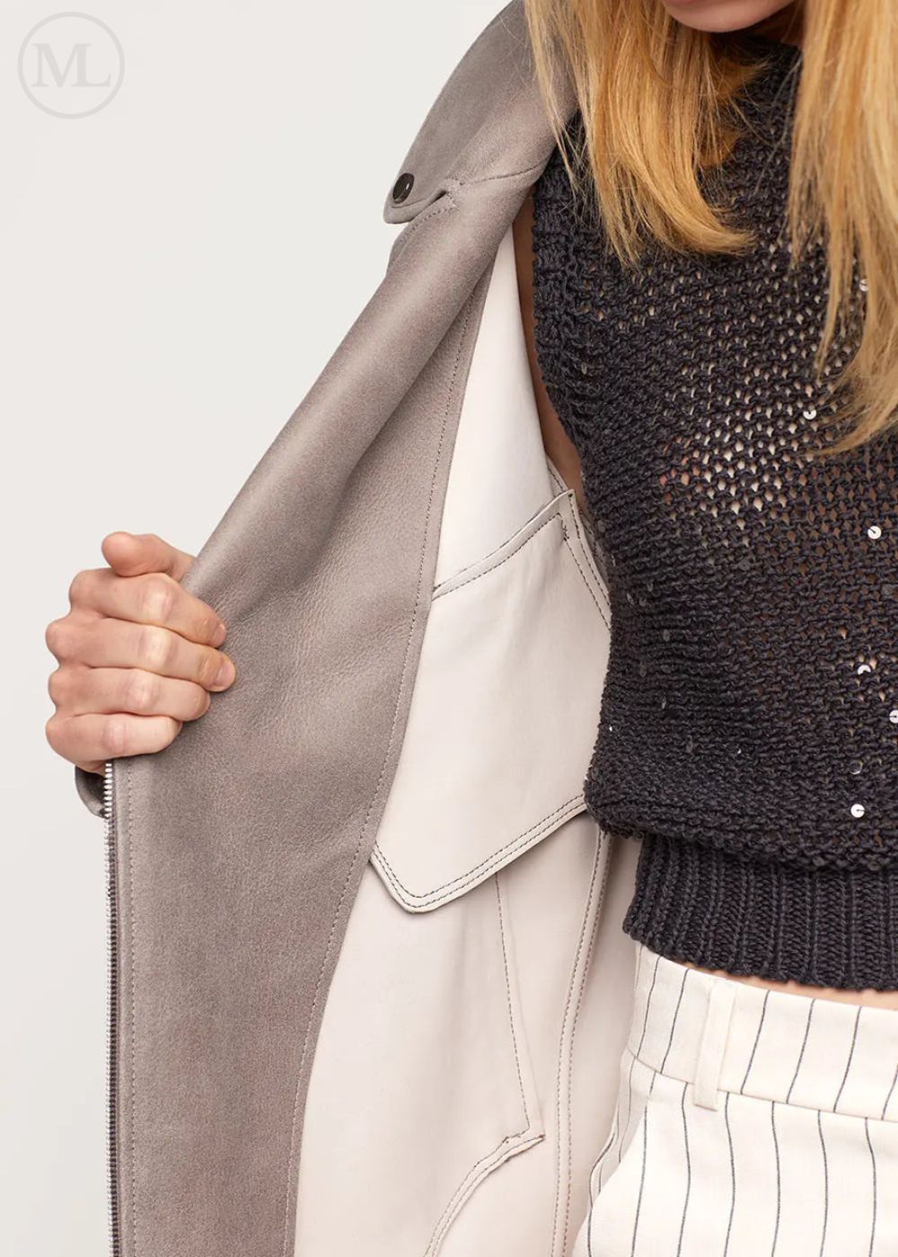 Woman wearing a grey Oversized Nubuck Leather Biker Jacket black sequin sweater, and white pants on a light background