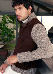 Man wearing a dark brown jacket over a gray sweater in an outdoor setting