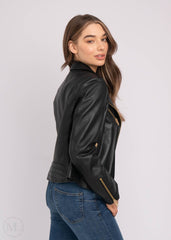Woman wearing a black leather biker jacket and blue jeans on a white background