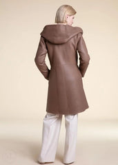 Woman wearing a beige shearling leather coat with a hood on a beige background