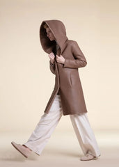 Woman wearing a beige shearling leather hooded coat on a beige background