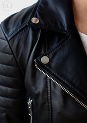 Close-up of a black leather biker jacket with silver buttons and zipper.