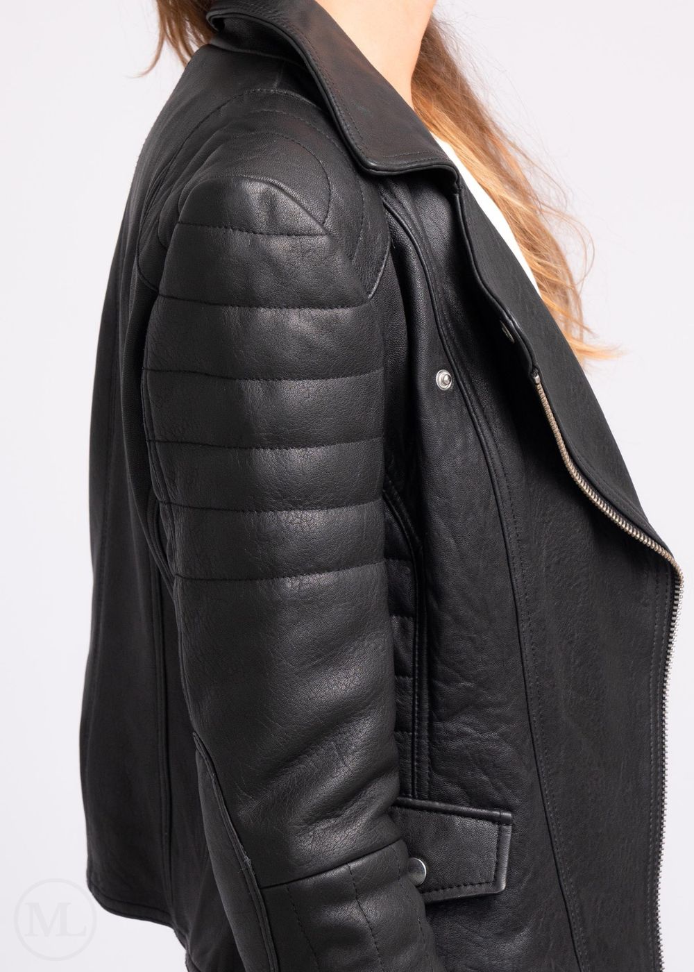 Side of a black leather jacket worn by a woman on a white background