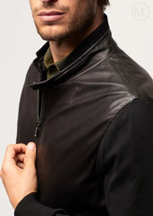 Man wearing a black leather bomber jacket on a plain background