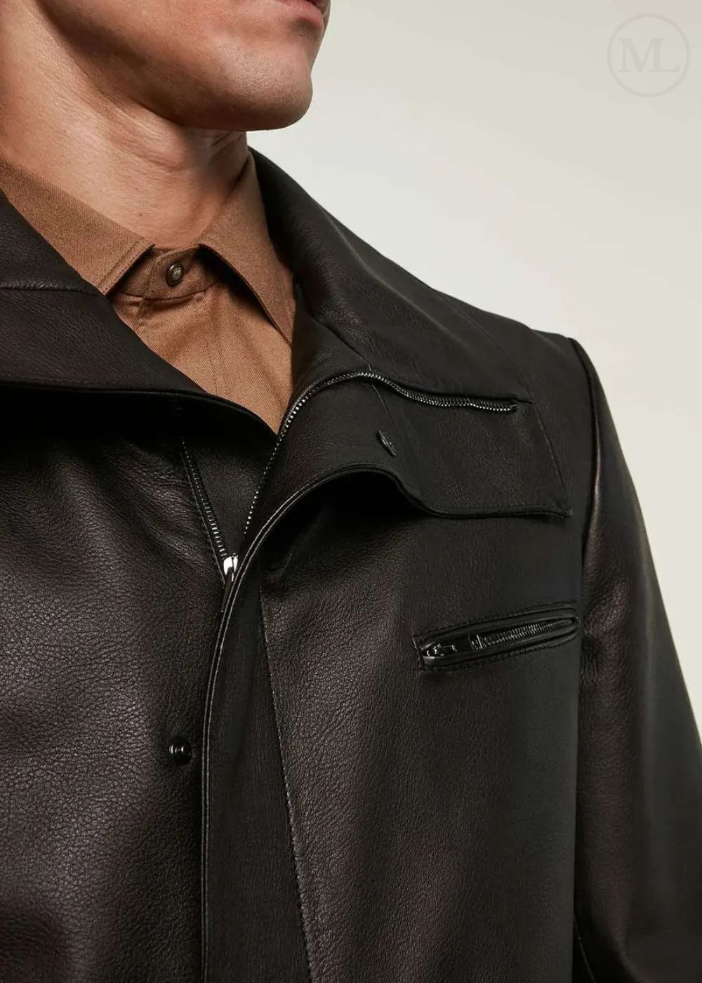Close-up of a man wearing a black leather jacket over a brown shirt.