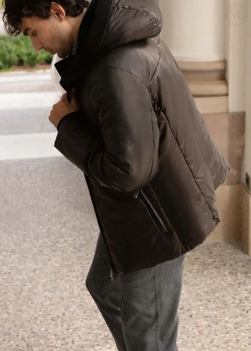 Man wearing a Black leather jacket outdoors on a stone surface.