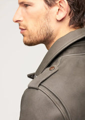 Close-up of a person wearing a olive khaki leather biker jacket with a plain background