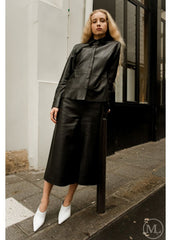 Woman wearing a black leather shirt standing on a city street.