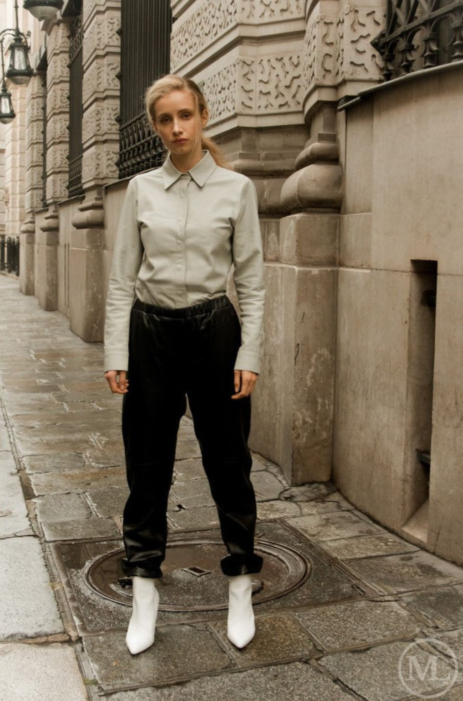 woman standing on a city street wearing a ivory leather shirt, dark pants, and white boots.