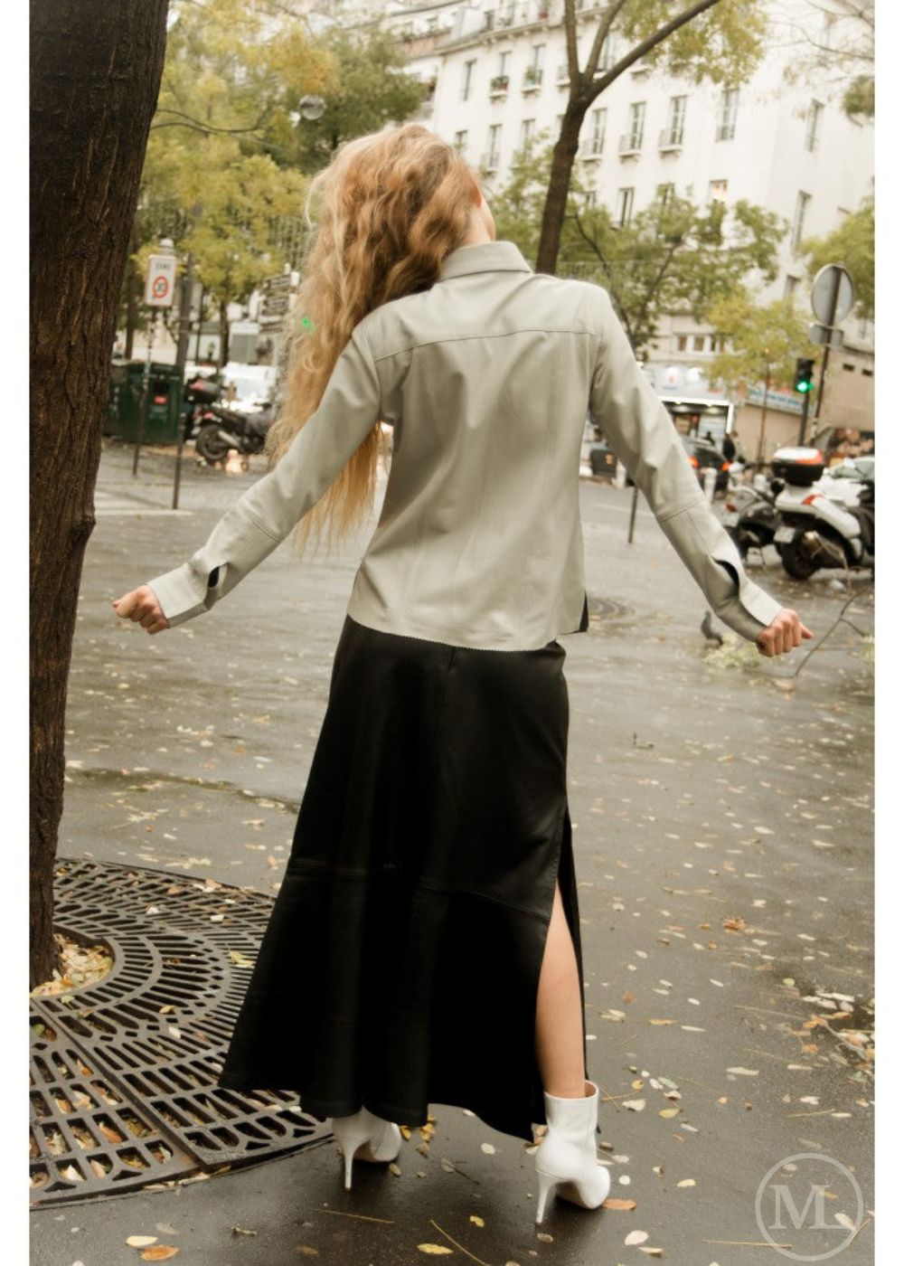 Woman walking on a city street wearing a ivory leather shirt and black skirt.