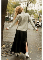 Woman walking on a city street wearing a ivory leather shirt and black skirt.