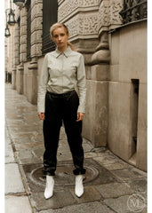 woman standing on a city street wearing a ivory leather shirt, dark pants, and white boots.
