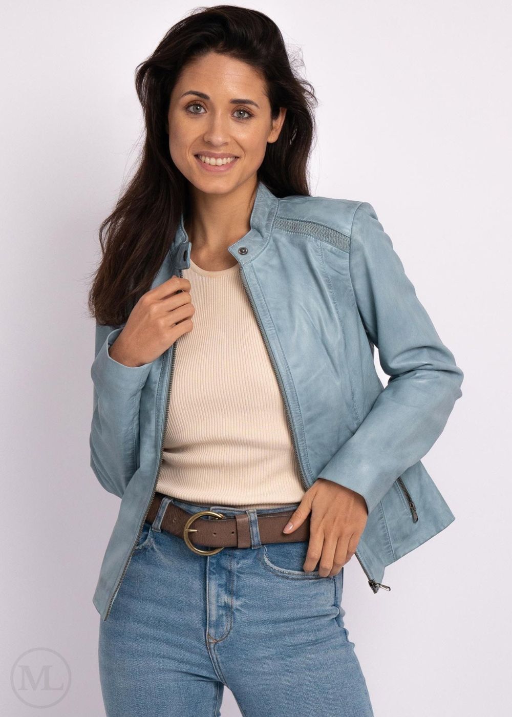 Woman wearing ice blue leather biker
jacket over a beige sweater and blue jeans on a white background