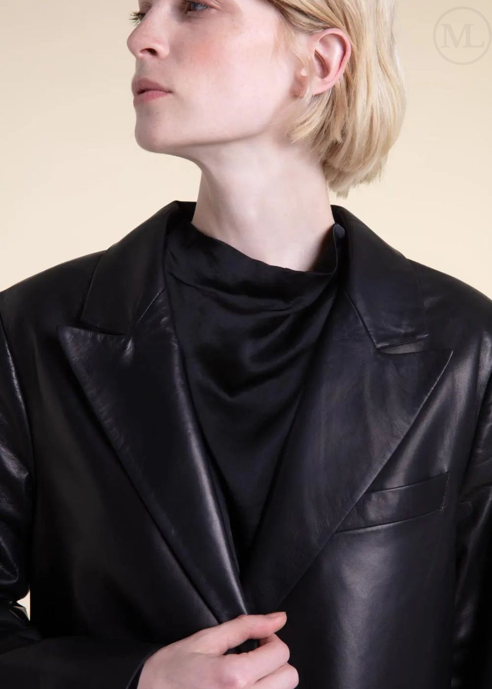 Woman wearing a black leather blazer jacket with a plain background