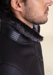 Close-up of a dark grey coat with fur collar on a beige background