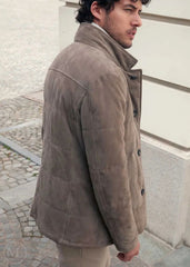 Man wearing a camel suede leather jacket standing on a street.