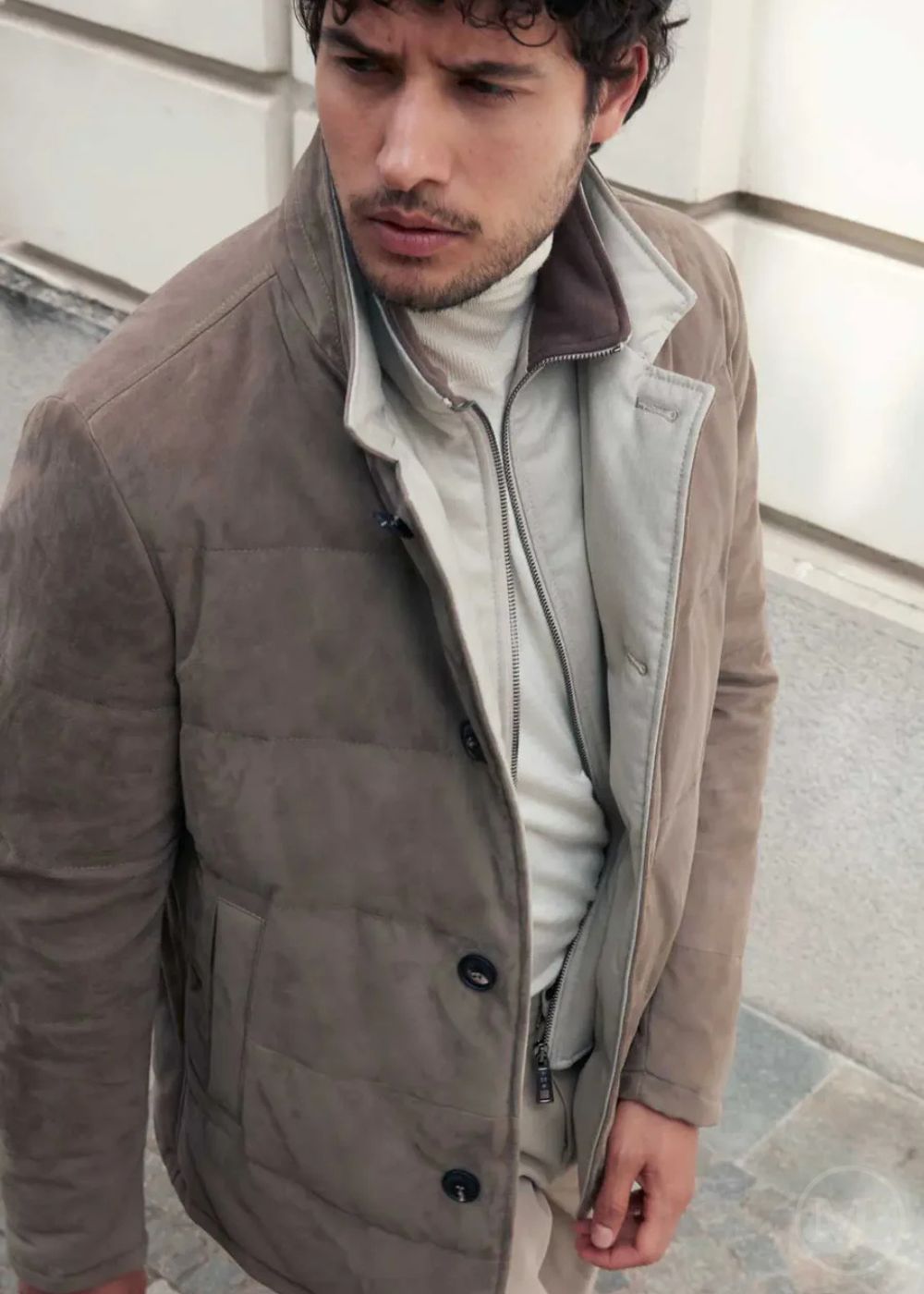 Man wearing a camel suede leather jacket with a neutral background