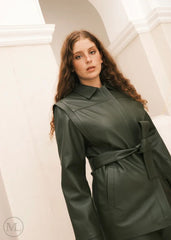 Woman wearing a green leather Coat jacket with a belt, standing against a neutral background.