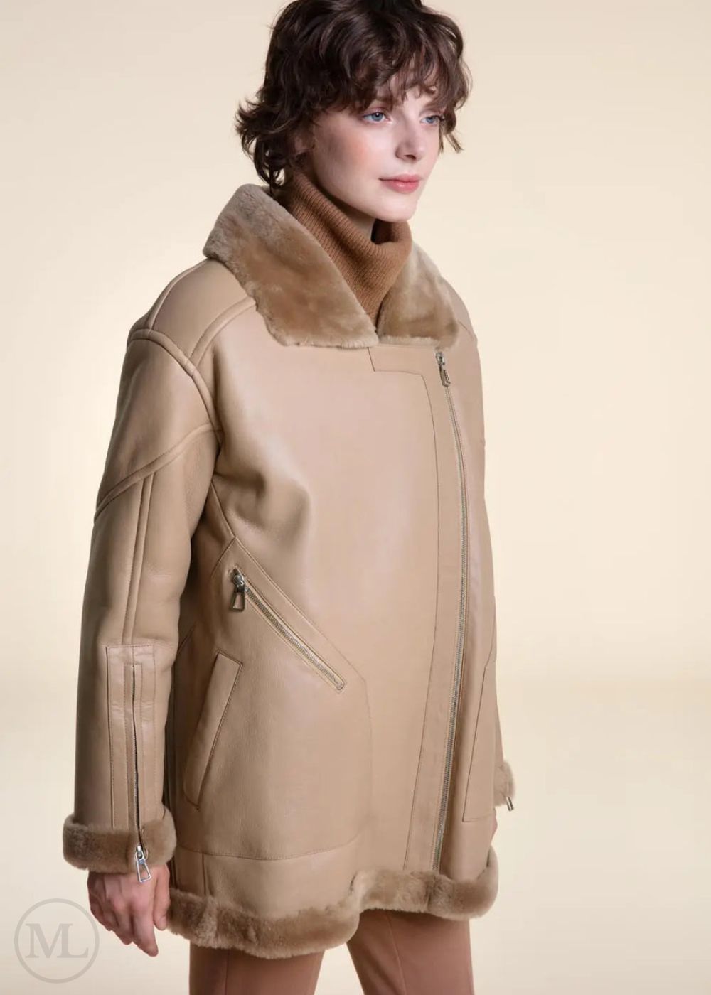 Camel shearling coat with fur trim worn by a model on a beige background