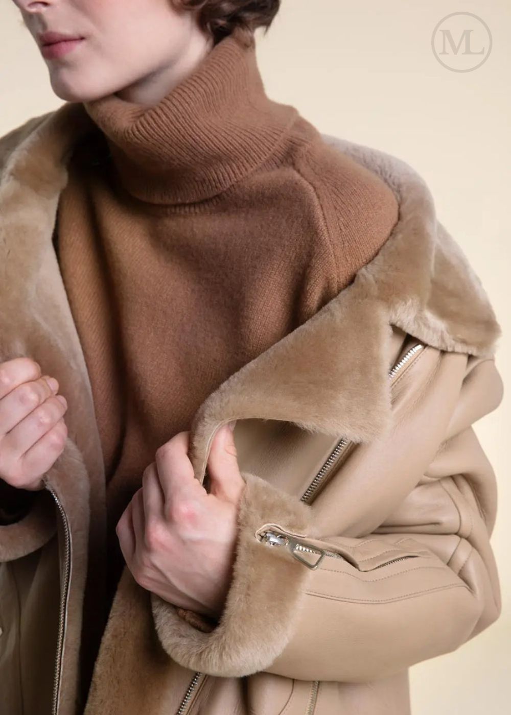 Close-up of a women wearing a shearling leather coat with fur lining on a beige background