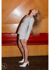 Woman wearing a Lvory Leather Blazer Coat against a wooden wall.