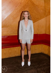 Woman wearing a Lvory Leather Blazer Coat against a wooden wall.